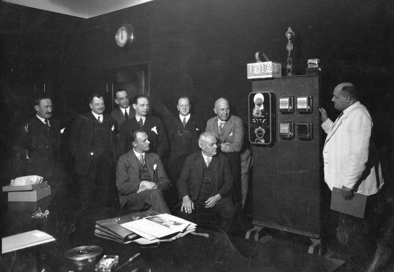 Demonstratie van een chocolade-automaat, jaren dertig. In het midden kijkt directeur Alphons van Iersel naar de camera (coll. F. van Iersel)